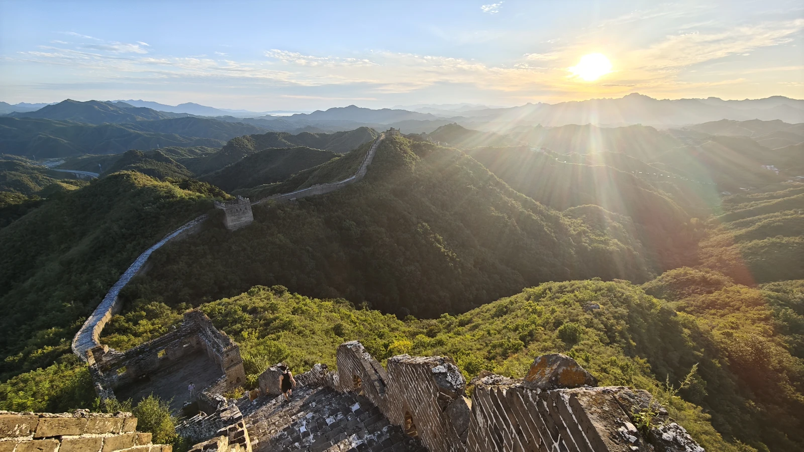 Sunbeams over mountain ridges and the Great Wall at Jinshanling in evening light