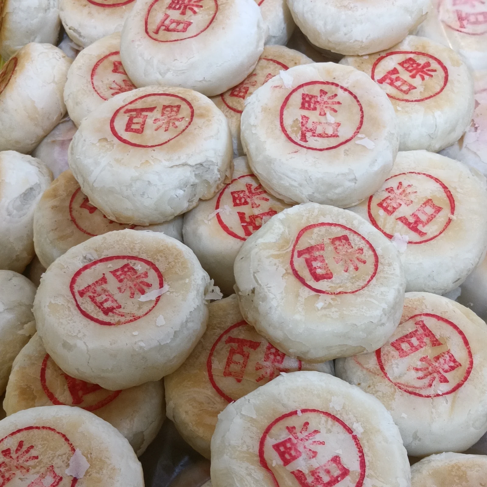 Stacks of flaky Suzhou-style mooncakes marked with red bakery stamps